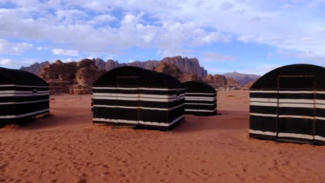 Beduinenzelte-In-Der-Roten-Sandigen-Arabischen-Landschaft-Der-Wadi-Rum-Wüste-In-Jordanien,-Schwenken-Von-Rechts-Nach-Links,-Roter-Sand-Und-Berge