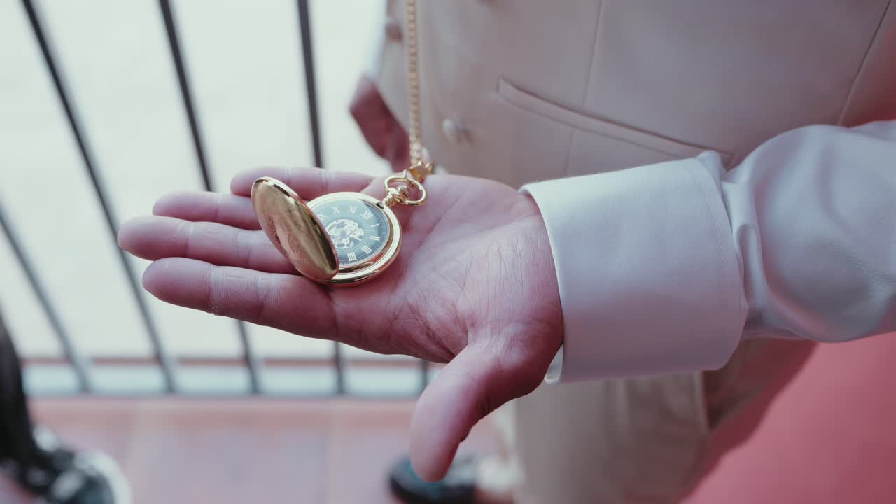 close up of a man in formal attire holding a golden pocket watch gently in his palm