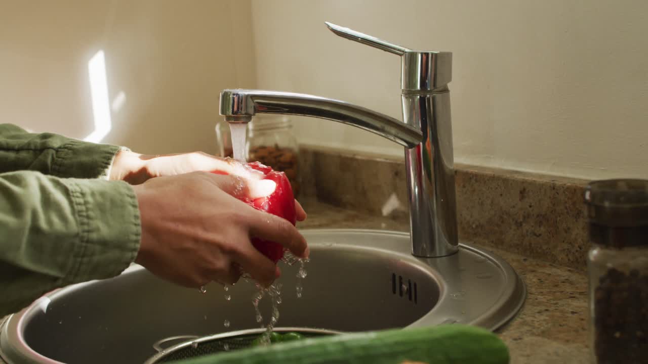 video de las manos de una mujer biracial lavando verduras