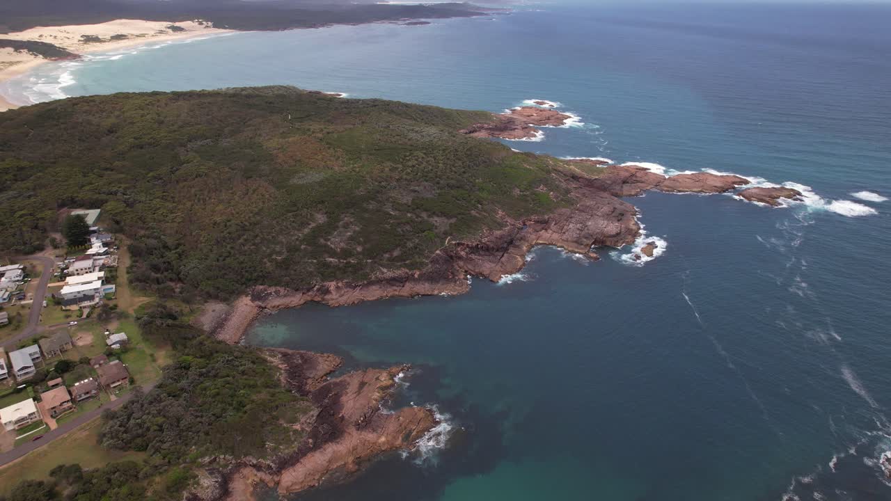Promontorio di Boat Harbour ricoperto di vegetazione a Port Stephens, Nuovo Galles del Sud, Australia. Ripresa aerea in allontanamento.