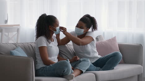 sisters wearing masks on a couch