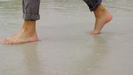 Low-section-of-Businessman-walking-barefoot-on-the-beach-4k