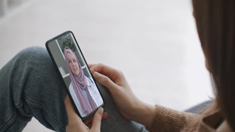 Woman-using-medical-app-on-smartphone-consulting-with-doctor-via-video-conference.-Female-using-online-chat-to-talk-with-family-therapist-and-checks-possible-symptoms-during-pandemic-of-coronavirus.