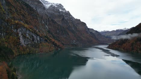 Slow-forward-pan-shot-of-the-lake-in-the-valley-between-the-hills-with-snow-capped-summits