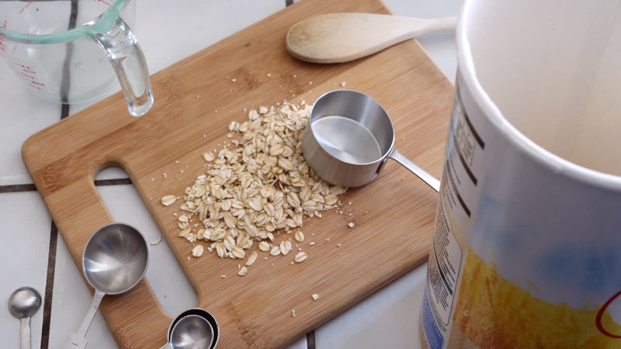 Oats whole grain cereal being poured with kitchen utensils for a healthy oatmeal breakfast TOP DOWN