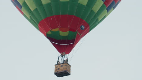 travellers drifting in colorful hot air balloon above open field at dusk with distant second balloon enhancing sense of serene aerial adventure and sky exploration over lush green fields