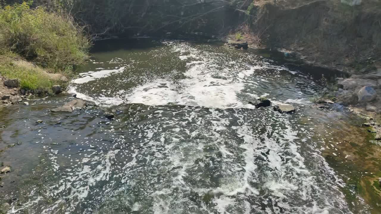 View of polluted river with foamy water, environmental issues and water contamination.