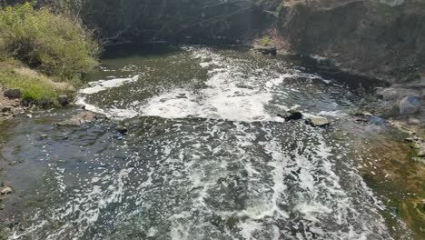 view of polluted river with foamy water, environmental issues and water contamination.