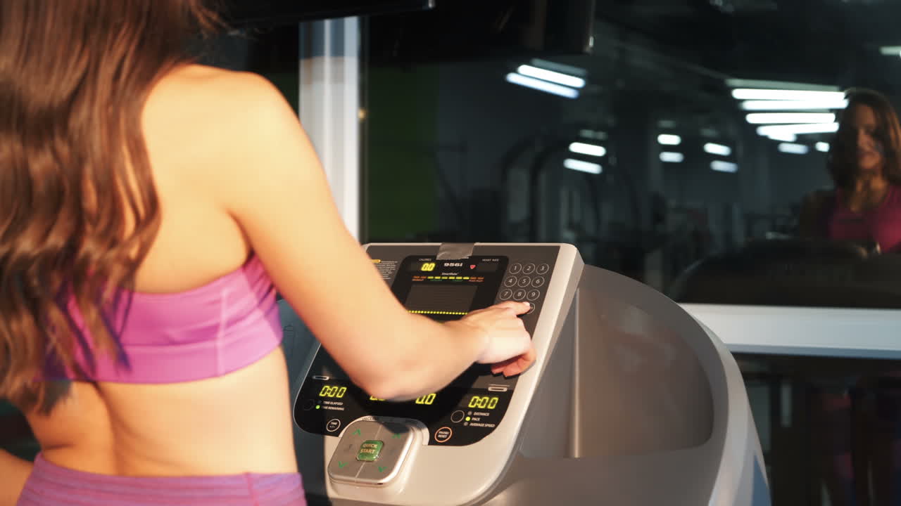 Fitness woman walking on treadmill for cardio training in gym club. Sports woman using screen on treadmill for settings cardio exercise in sports club