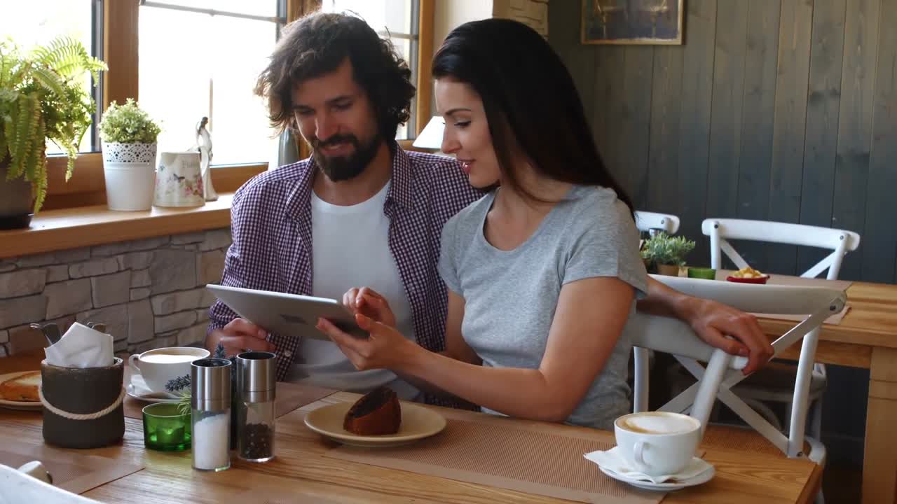 Couple using digital tablet in cafe