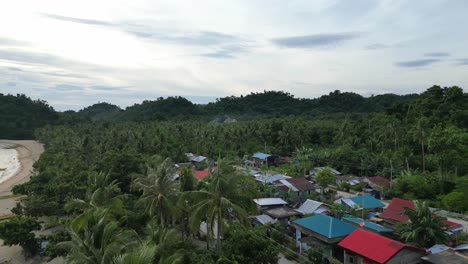 aerial, establishing, panning shot of small island town and majestic beach with bangka boats during sunset