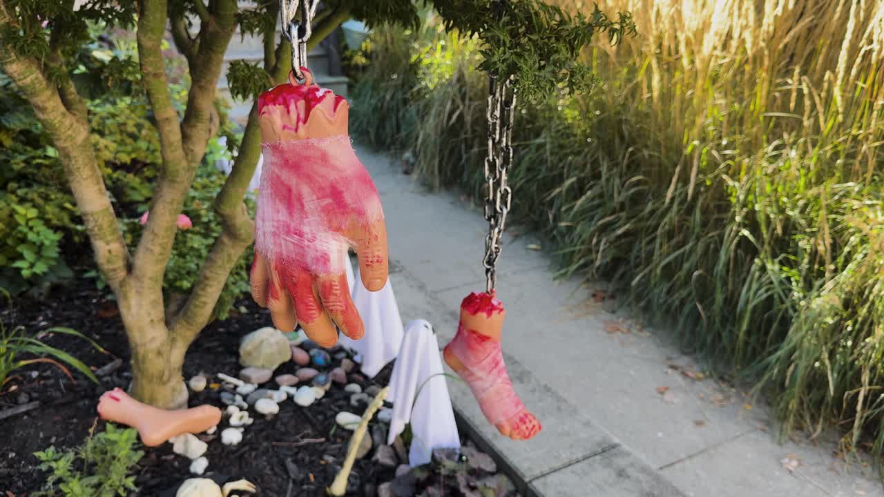 Low-angle shot showing Halloween decorations in Toronto, including a bloody hand and foot hanging from a tree with small ghosts below
