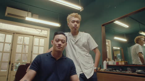 asian barber and male client posing in vintage barbershop