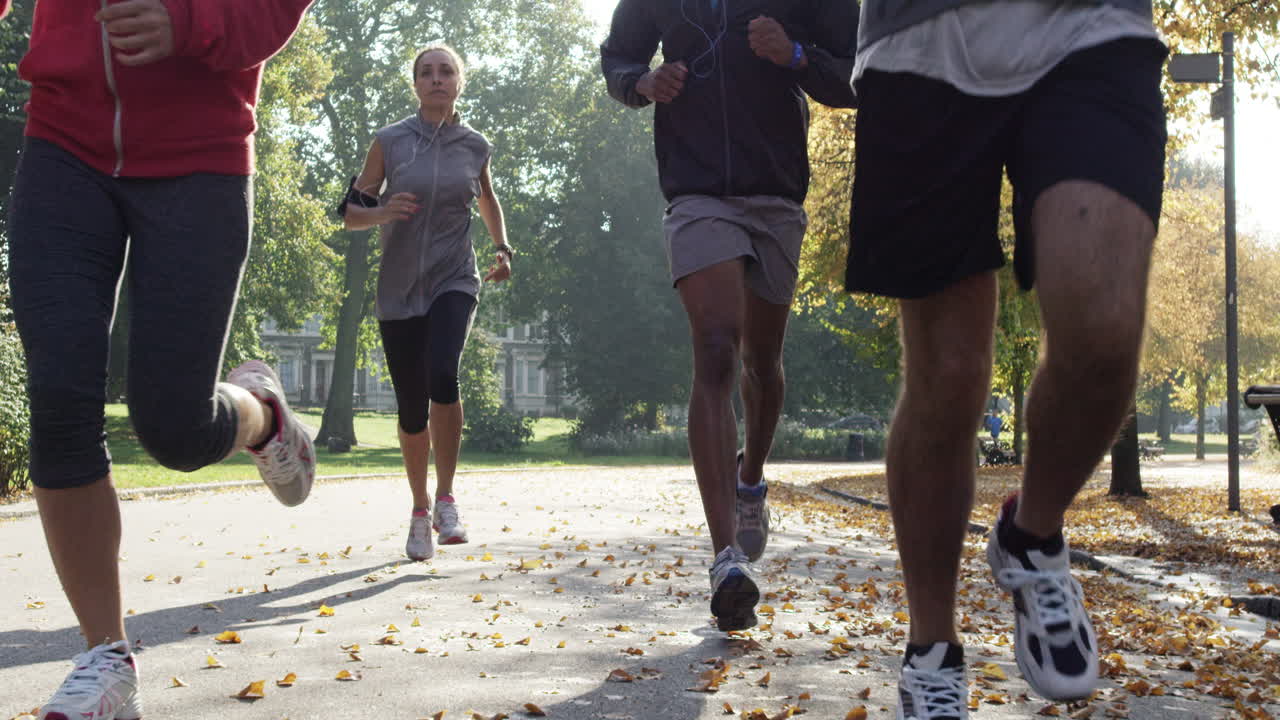 Group of runners running in park wearing wearable technology connected devices