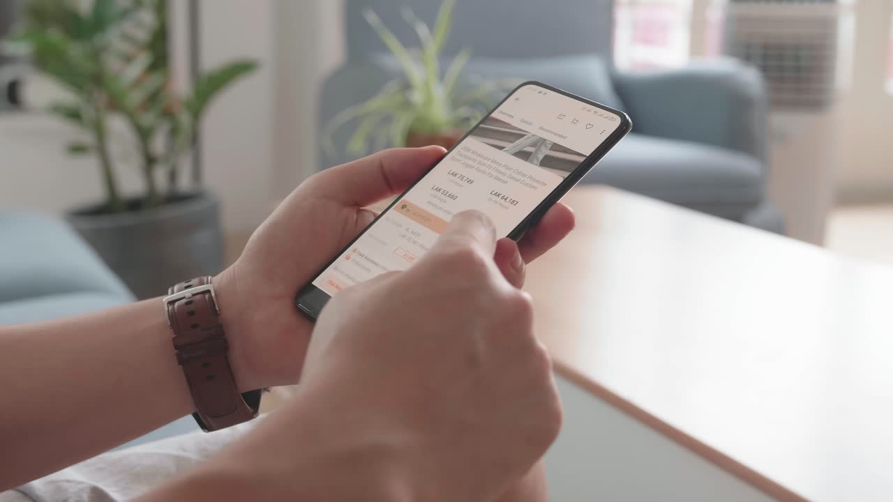 Close Up Of Man Hand Holding Smartphone And Doing Online Shopping At Home, Male Looks At Goods In Online Store Clothing