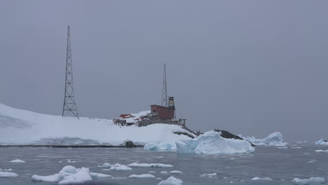 sailing by coast of antarctica, research station building, snow and floating ice, slow motion