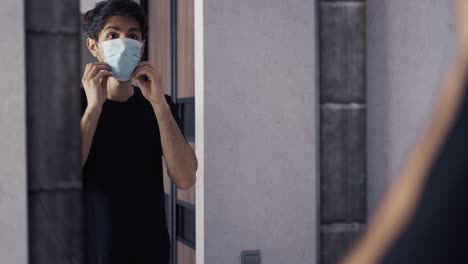 Dark-haired-man-in-front-of-the-wardrobe-put-on-a-mask-at-home