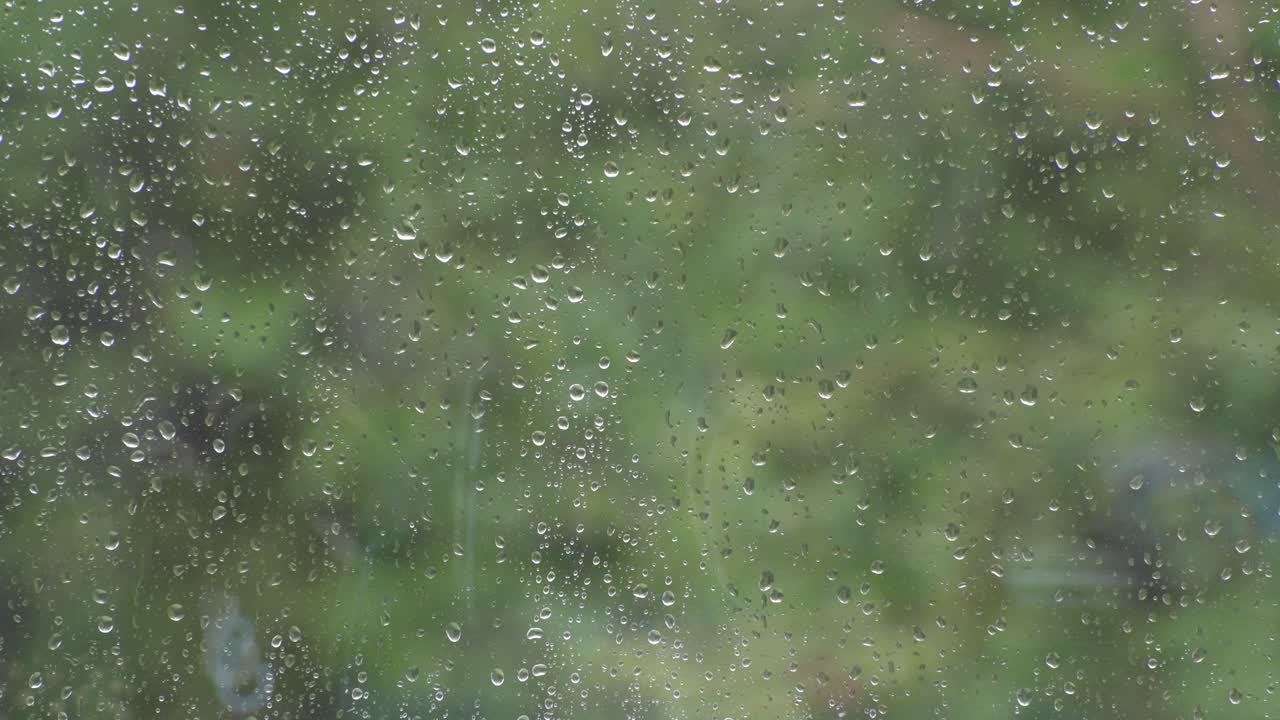 A close-up shot of a window while it is raining