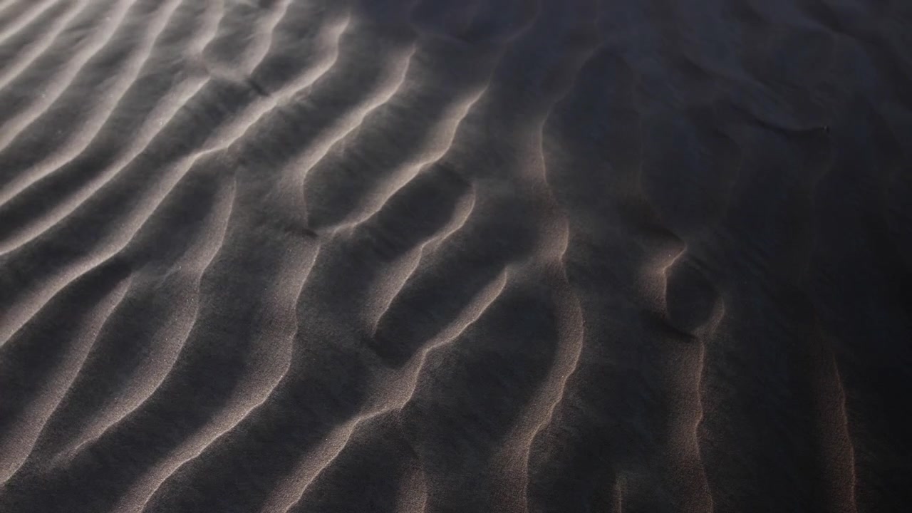 Sun shines on desert sand blowing in middle eastern desert landscape near Dubai in the United Arab Emirates.