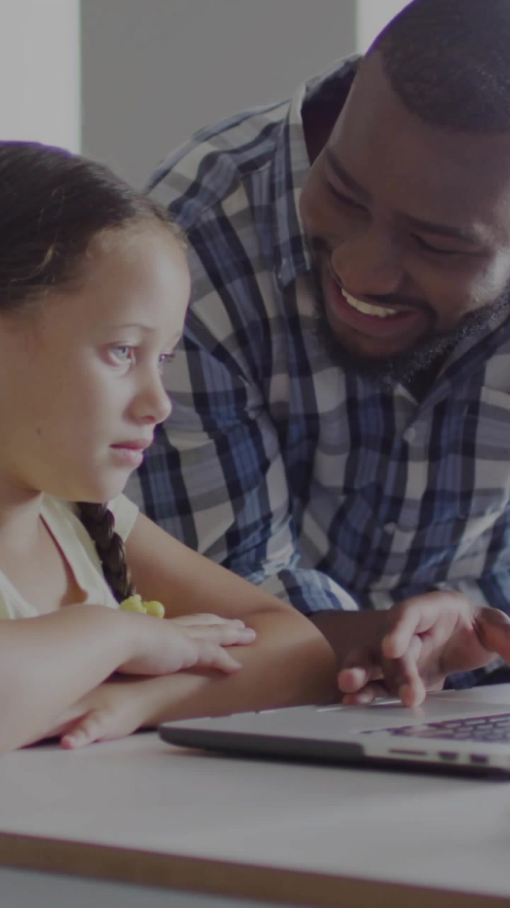 Vertical video: Dad teaching girl, tapping laptop, causing charts fading and growing for learning