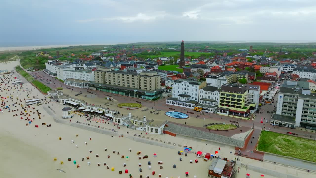 Borkum Island beachfront promenade with historic hotels, spa resorts and vast beach with strandkorb chairs. Aerial drone view