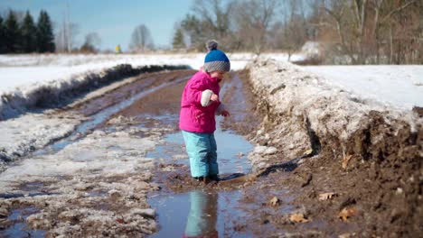 young girl jumps into mud puddle in slow motion