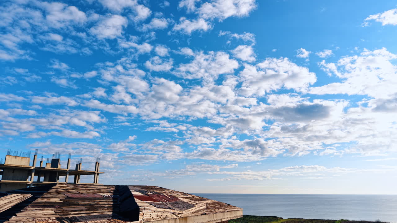 Salendo sul tetto in legno dell'edificio a più piani in costruzione, si rivela una vista sull'ampio paesaggio marino e sul cielo blu coperto di nuvole soffici.