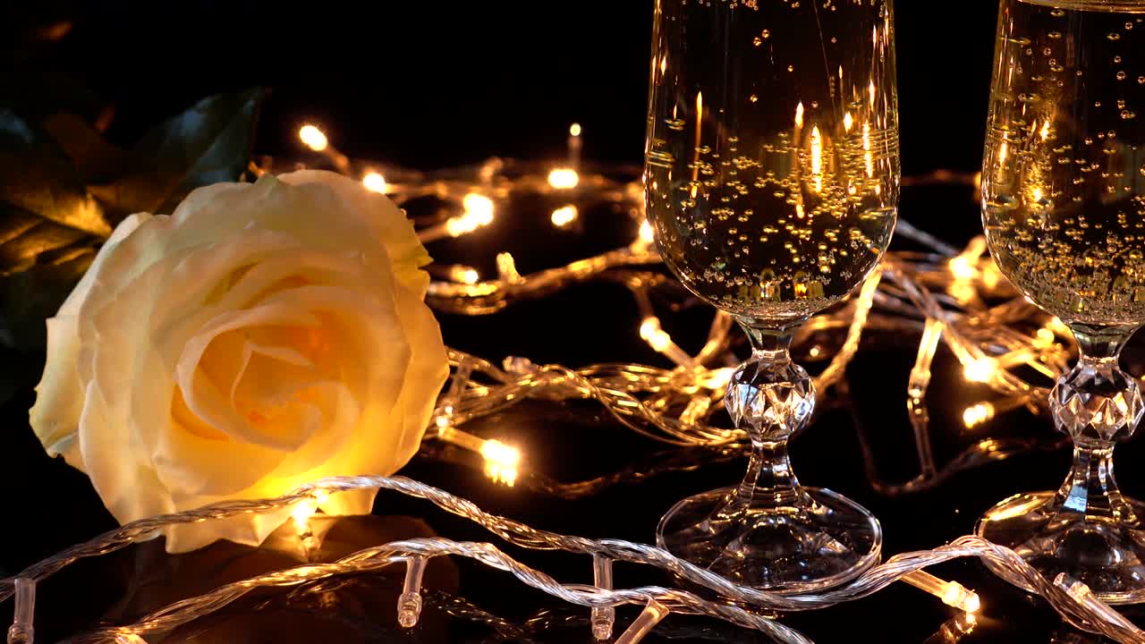 Calici da champagne e una rosa sullo sfondo di ghirlande luminose