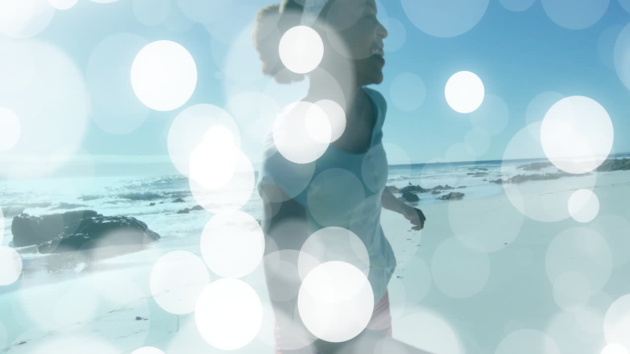 Couple running hand in hand along sunny beach for travel marketing, using animated bokeh circles