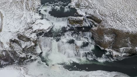 Toma-Aérea-Cinematográfica-De-Arriba-Hacia-Abajo-De-La-Impresionante-Cascada-De-Reykjafoss-Durante-El-Helado-Día-De-Invierno-En-Islandia---Inclinado-Hacia-Arriba