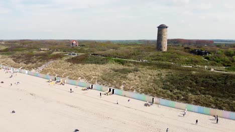 large lighthouse next to a beach in the netherlands