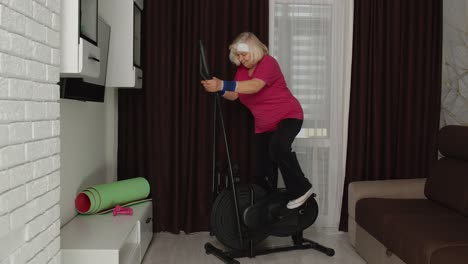 Active-healthy-senior-old-mature-woman-in-sportswear-using-orbitrek,-training-cardio-workout-at-home