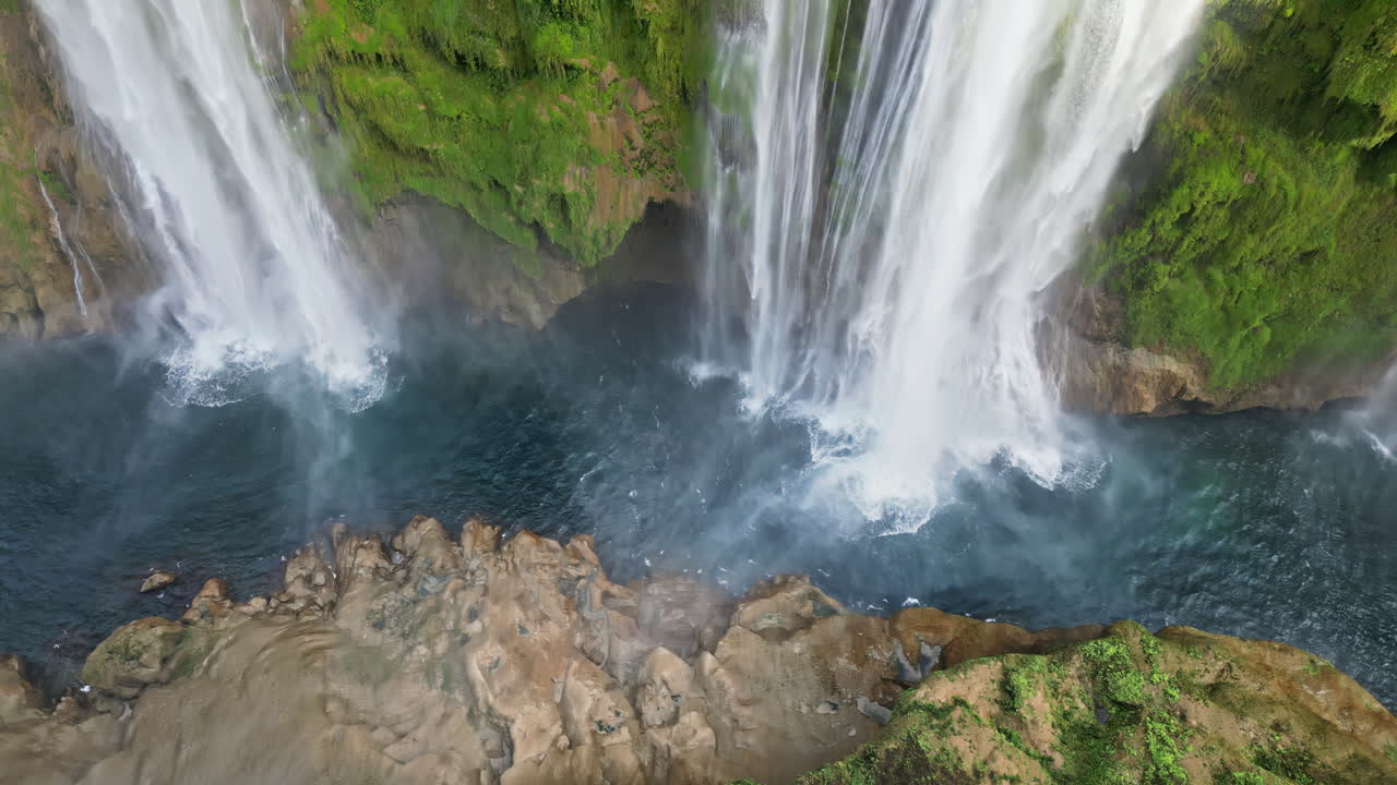 Aerial drone view of Tamul Waterfall cascading down green cliffs into a turquoise pool below