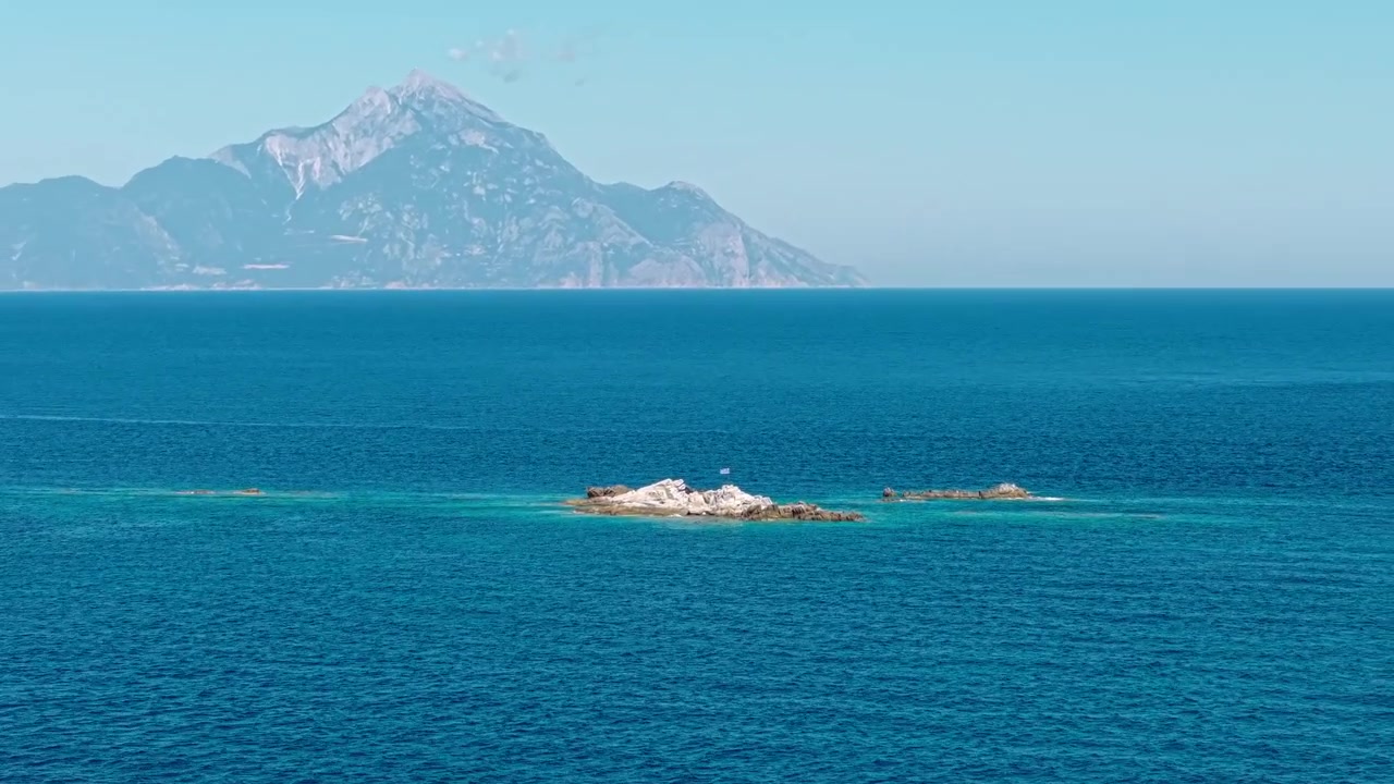 アトス山とギリシャ国旗が掲げられた小さな小島、ドローンによる空撮