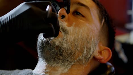 male barber shaving a clients beard 4k