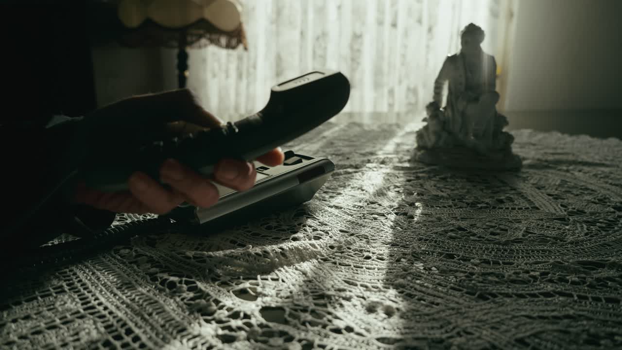 Person making call on retro push button telephone in ambient lit room