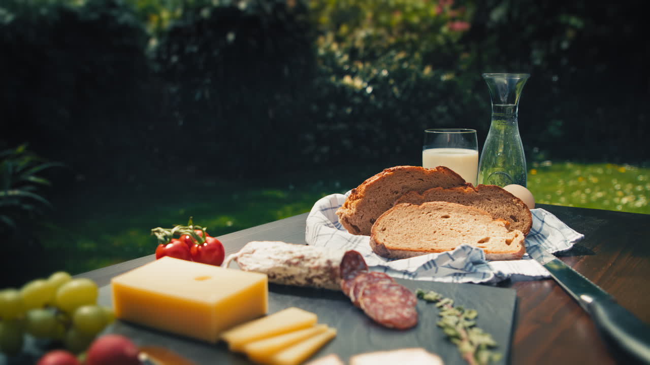 Vibrant outdoor scene with a charming garden table showcasing a delicious spread of salami, cheese, and bread. Perfect for food-related marketing campaigns and enticing culinary promotions