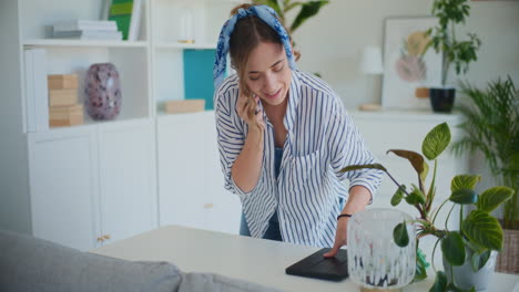 Woman-Chatting-on-Mobile-While-Cleaning-Living-Room