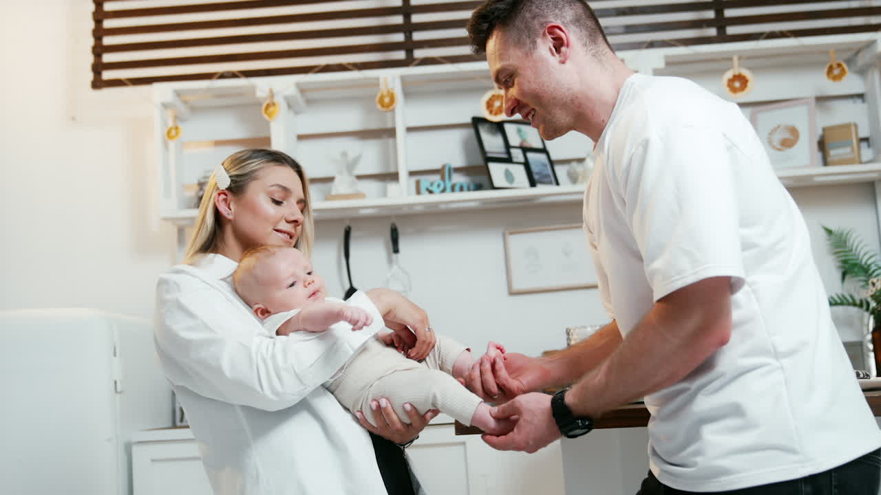 Beautiful young couple with their newborn child. Blonde woman holding a baby and man hold infant's feet.