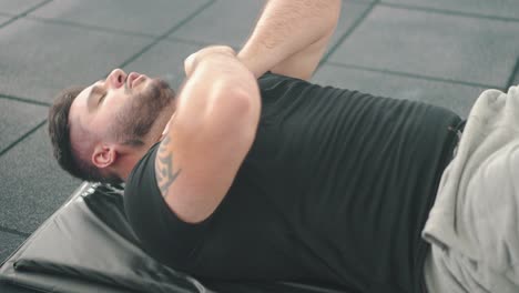 side shot of an strong young man exhausted doing crunches in the gym