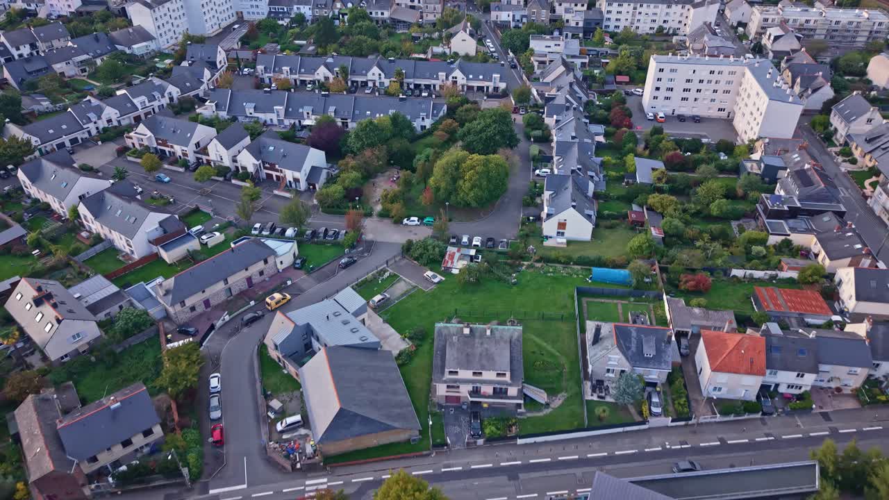 Aerial drone view of a quiet residential neighborhood in Rennes, France. Features traditional houses with private gardens and tree-lined streets near the La Courrouze district