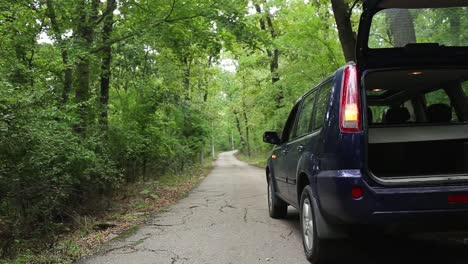 open trunk and flashing headlights of a car on the side of a country road