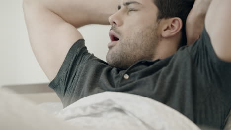 handsome man waking up in morning. happy man stretching on bed in house.