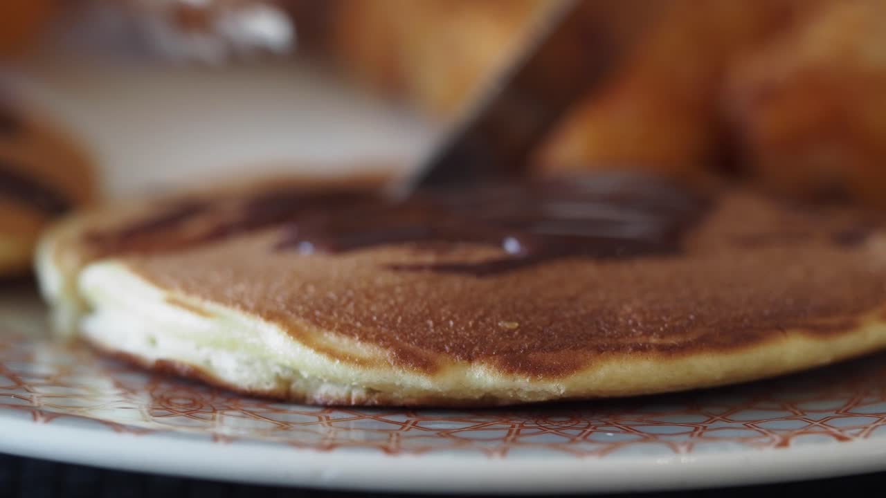 Close-up of a pancake with chocolate sauce being cut