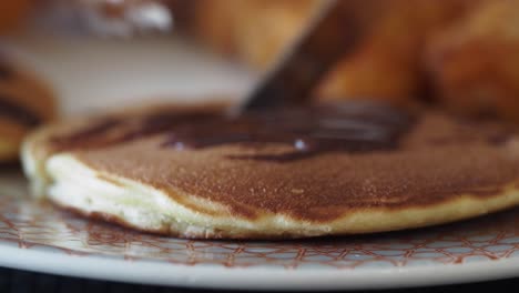 close-up of a pancake with chocolate sauce being cut