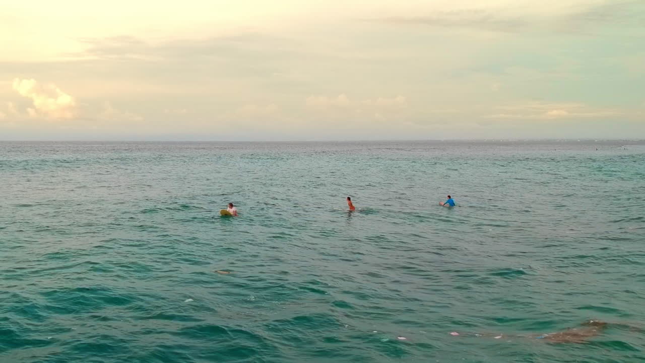 surfistas en la playa de bali, indonesia esperando la ola perfecta para montar en una puesta de sol - disparo de drones