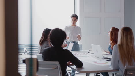 Blick-Durch-Die-Tür,-Während-Die-Chefin-Eine-Präsentation-Vor-Einem-Team-Von-Geschäftsfrauen-Hält,-Die-Sich-Am-Tisch-Treffen