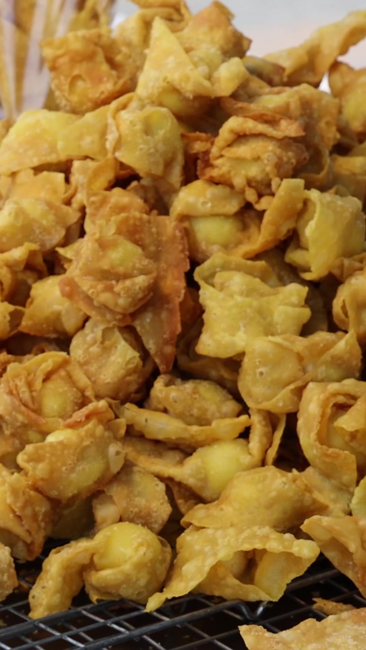 Un'inquadratura verticale che si concentra su un mucchio di wonton fritti croccanti e dorati in esposizione