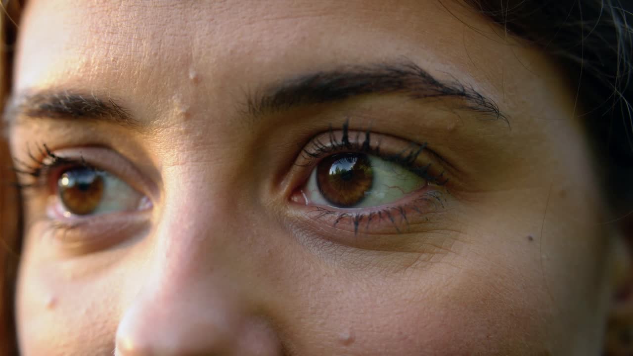 Gravando olhos femininos mudando o olhar e piscando em close-up durante a hora dourada, revelando detalhes da pele