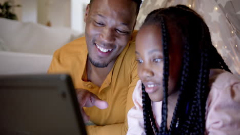 Happy-african-american-father-with-daughter-using-tablet-at-teepee,-slow-motion